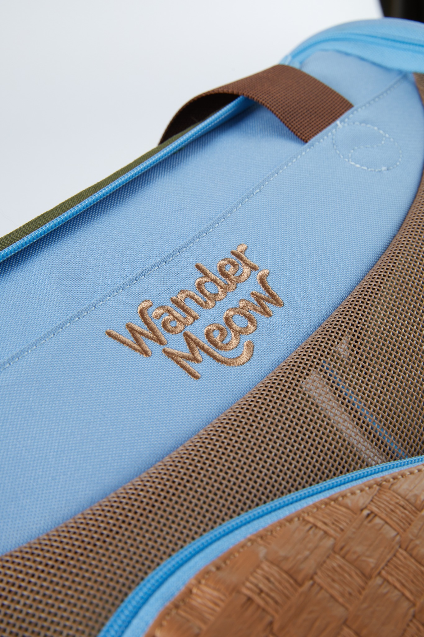 Close view of the blue Wander Meow carrier showing the curved boundary between its breathable mesh and sheltered lower panel.