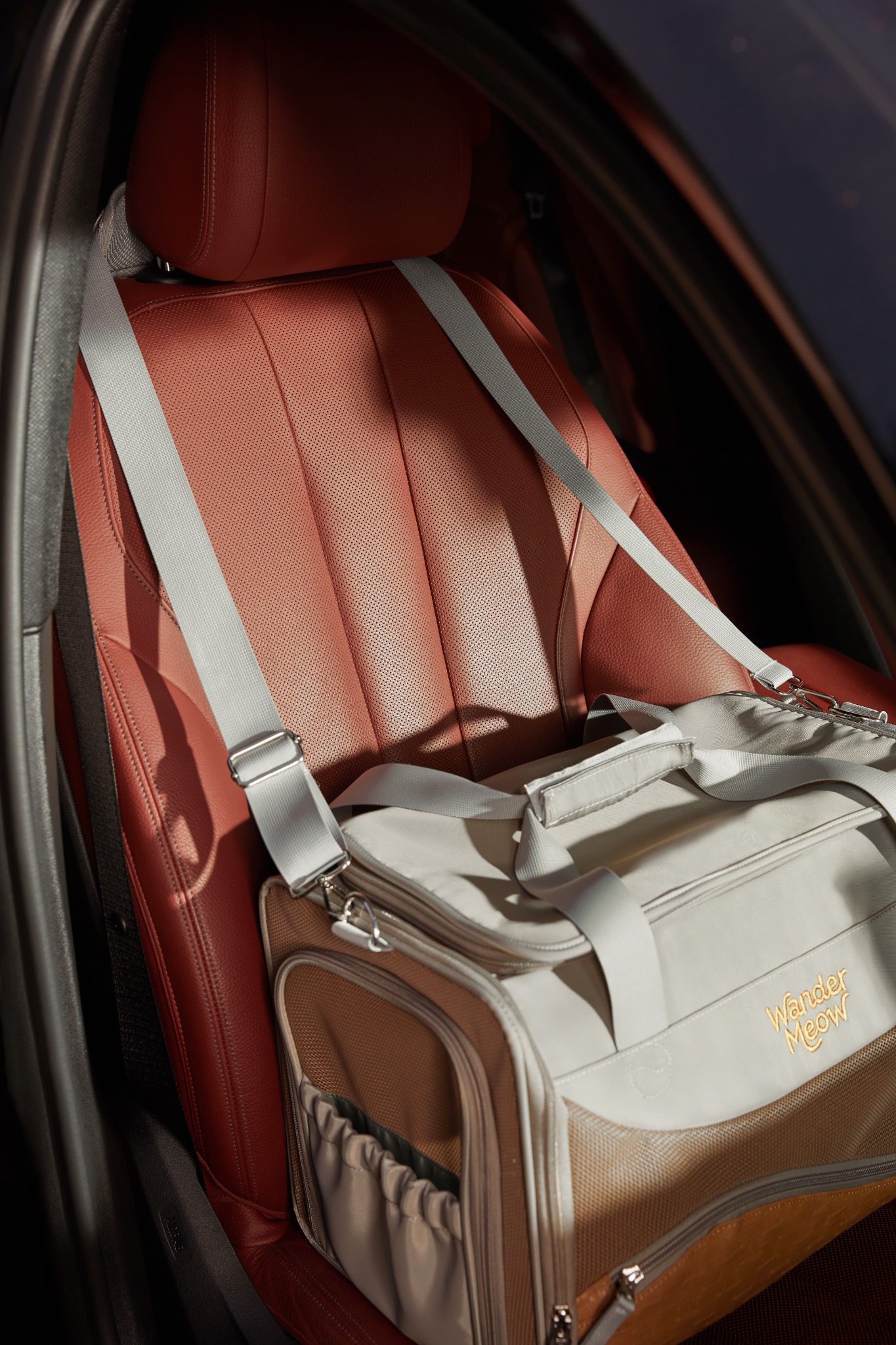 Fully closed gray Wander Meow carrier positioned on a car seat with its shoulder strap in place.